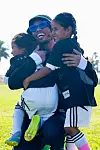 Anderson .Paak holding two kids dressed in soccer gear.