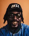 MoRuf with a gold grill and a hat that says 'jazz.'