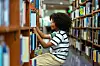 Young girl finding book on bookshelf in the school library. Education knowledge Concept