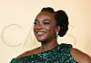 Wunmi Mosaku smiling in a green sequined one-shoulder gown at the Oscars.