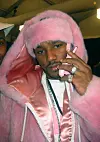 Cam'ron wearing a pink fur coat and hat, holding a pink flip phone to his ear.