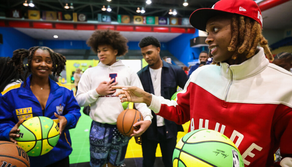 Lil Durk interacts with students holding STARRY basketballs on a court at Jackson State University.