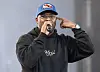 Schoolboy Q raps into a microphone onstage wearing a black hoodie and blue cap