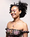 Smiling woman with curly hair posing in a studio against a light backdrop