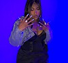 Woman posing in blue light with jeweled jacket and long nails