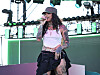 Kehlani performing on an outdoor stage at the REVOLVE Festival with mic in hand.