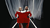 Two models stand on a lit runway sharing one large red suit before white curtains.