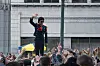 Jaafar Jackson as Michael Jackson stands above a crowd, waving in a city street scene.