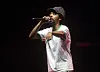 Earl Sweatshirt performing on stage with a microphone at an outdoor concert