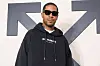Kid Cudi wearing a black hoodie and sunglasses at an Off-White fashion show.
