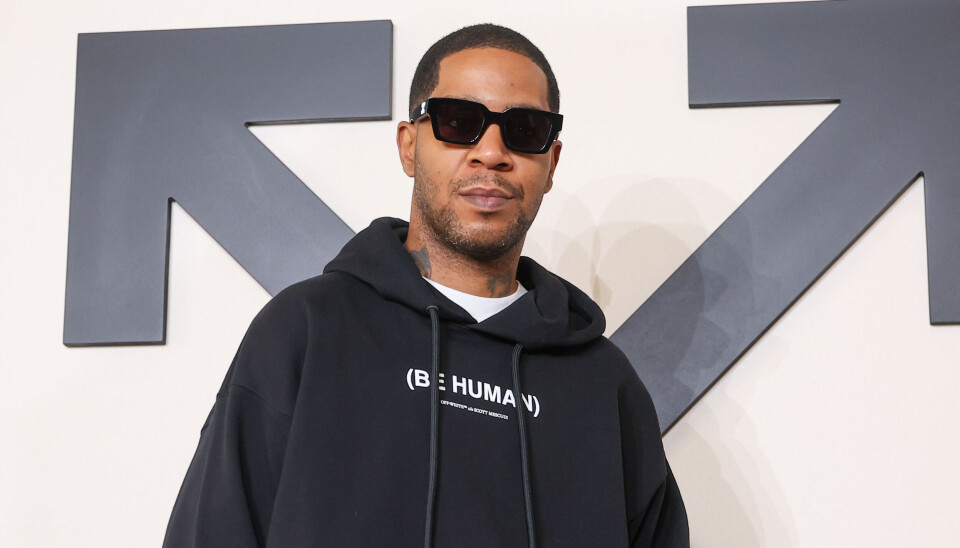 Kid Cudi wearing a black hoodie and sunglasses at an Off-White fashion show.