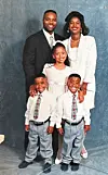 Family of five posing in a studio against a blue-gray backdrop.