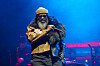 Black Thought of The Roots performs onstage beneath blue lights at a music festival.