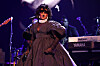 Lauryn Hill sings onstage in a dark gown at the Grammys, with a Yamaha keyboard behind her.