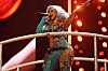 Cardi B performs on a lit concert stage in Newark with a microphone and sparkling outfit.