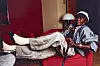 Miles Davis reclines on a red sofa in a room with red walls and a floor lamp.