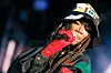 Singer in a patterned cap and red glove performs into a microphone on stage.
