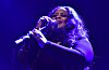 Maysa sings into a microphone on a blue-lit stage at the O2 Forum Kentish Town.