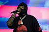 Westside Gunn performs on stage under pink and blue lights, wearing a black hoodie and mask.