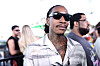 Wiz Khalifa wearing sunglasses at the REVOLVE Festival with people blurred behind him.