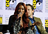 Keke Palmer speaking into a microphone at a Comic-Con panel with a man seated behind her.