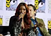 Keke Palmer speaking into a microphone at a Comic-Con panel with a man seated behind her.