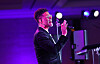 Eric Benét performs onstage with a microphone under purple lighting beside a keyboard.