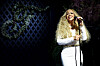 Mariah Carey performs in white on a garden-themed stage at a Tiffany & Co. event.