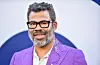 Jordan Peele smiles in a bright purple suit
