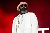 Black Thought wears an all-white suit and stands in front of a red background