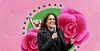 Kamala Harris holding mic in front of pink flower
