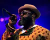 Black Thought wears a hat and sunglasses and hold a mic