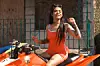 A girl in an orange tank top with tatoos smokes a blunt on an orange ATV.