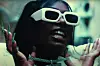 Mello Buckzz in glasses and holding her chain up for the camera. She's one of the best female rappers
