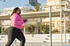 African American female athlete in sportswear and sneakers jogging on city street, one of many self care tips