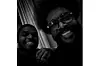 A grainy black and white photo taken selfie style of Rob Cave and Questlove.
