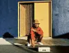 Musician and producer MNDSGN in burnt orange and khaki against a yellow door and cold blue wall.