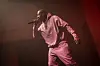 Freddie Gibbs on stage performing with a dark pink hoodie set on.