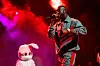 Freddie Gibbs wearing a tan two piece while performing on stage in front of a pink bunny.