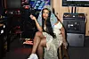 SZA holds a blunt and sits on a stool in an arcade.