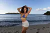 Singer Maeta on a beach with blue top and white skirt.