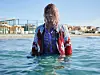 Michaela Coel in water with colorful jacket.