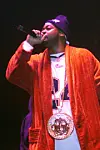 Rapper Ghostface Killah wearing orange robe and big chain holding mic best rap verses