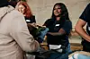 Smiling volunteer giving clothes to homeless woman at community center