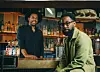Two Black men smiling at a nicely designed bar.