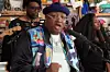 E-40 in a colorful coat in the middle of rapping.